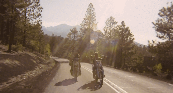 Fermoimmagine tratto dal film Easy Rider che riprende i due motociclisti interpretati da Peter Fonda e Dennis Hopper che attraversano una strada in mezzo a una foresta